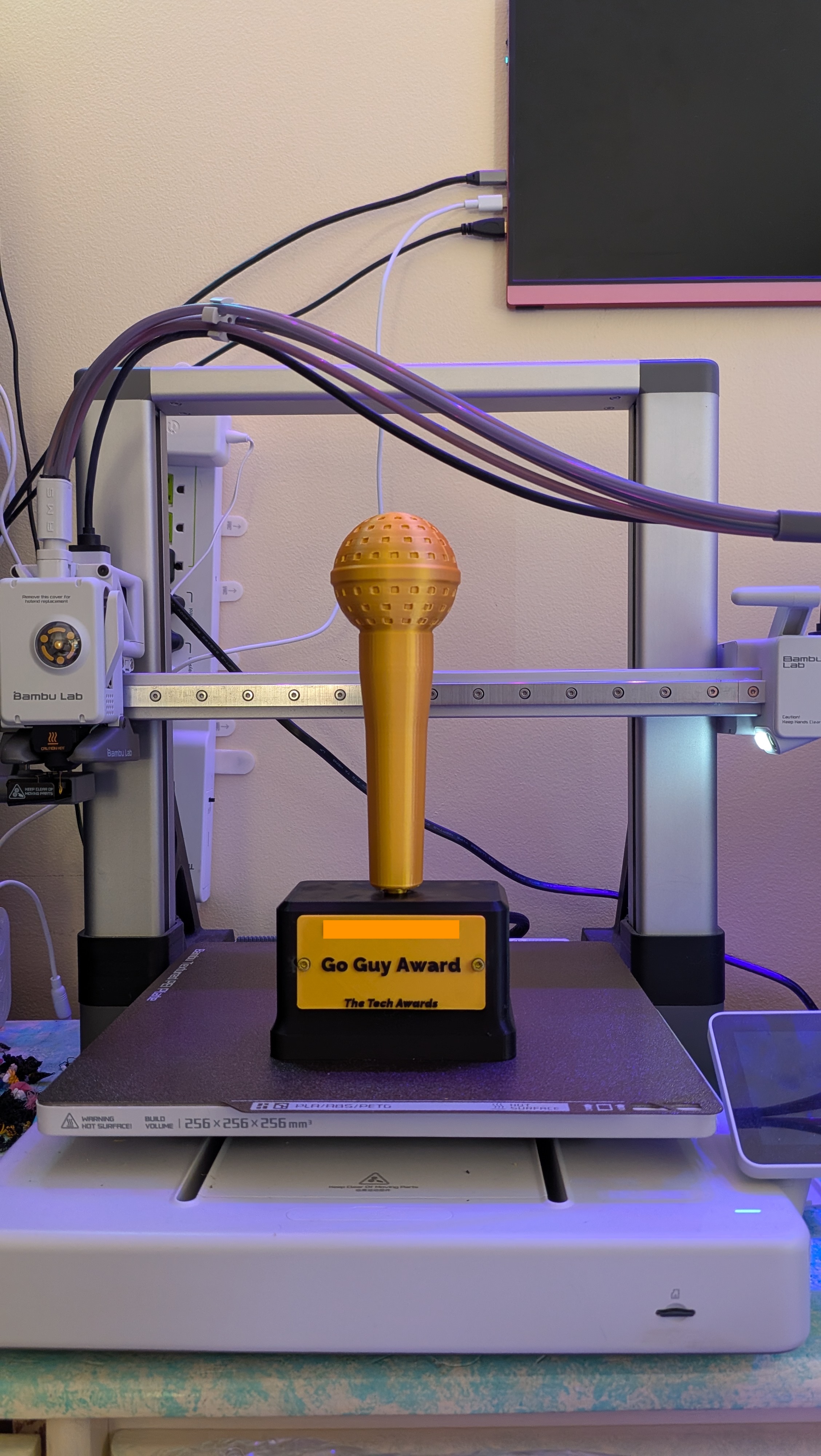 An awards trophy with a black base, gold nameplate, and gold microphone
