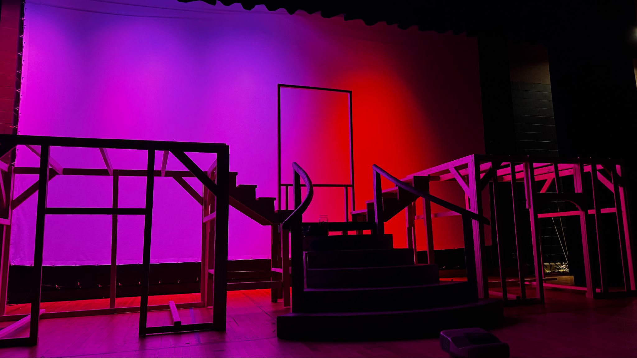 A cyclorama lit up purple and red. A set's bare studs is in front of the cyc.
